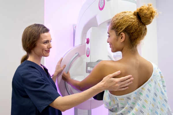 A radiologist guides a young woman during a mammogram.