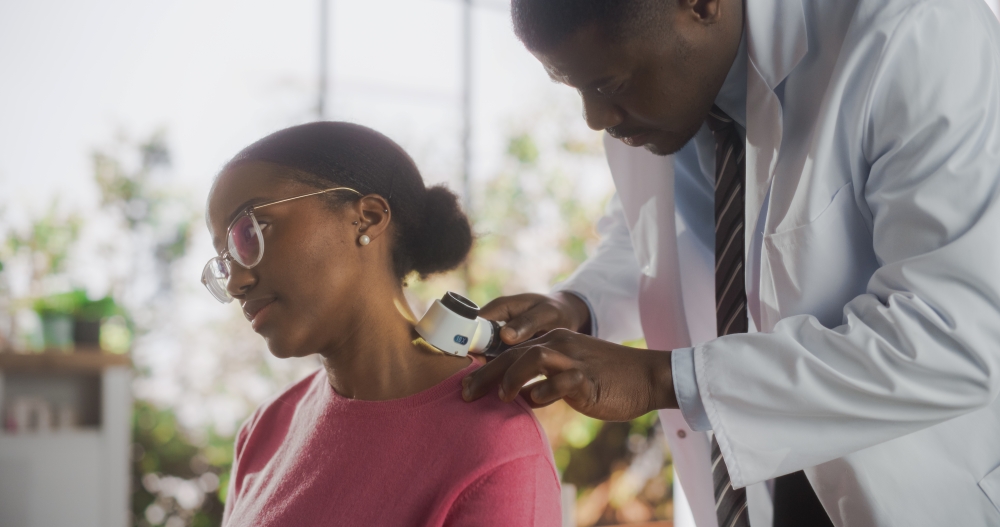 A doctor does a skin cancer screening on a young woman patient. 