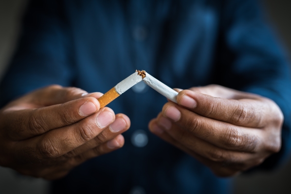 A closeup of a man's hands holding a cigarette that has been broken in half.