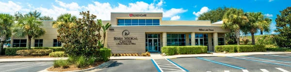 A wide shot of the front entrance of Rosen Medical Center, surrounded by palm trees and green landscaping.