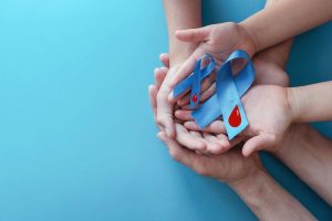 An adult and a child holding light blue ribbons for Diabetes Awareness Month.