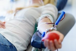 Young woman holding a toy heart while donating blood