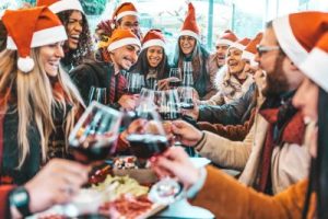 Happy people wearing Santa Claus hats having a Christmas dinner party.