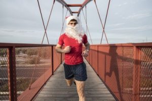 Santa Claus running on a bridge to burn fat after a Christmas party.