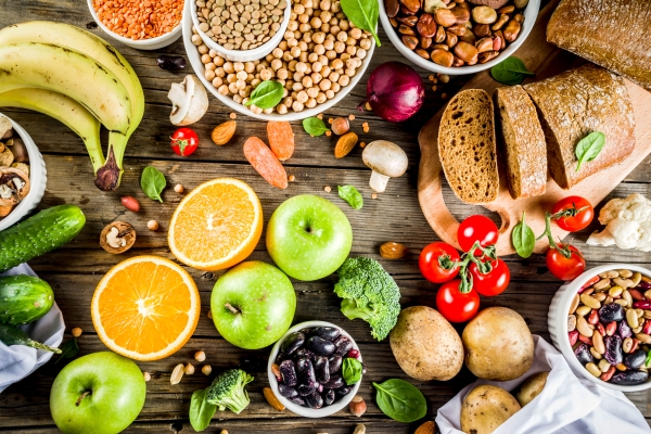 A display of foods representing healthy carbs, including fruits, potatoes, beans, and whole wheat bread. Carbs are part of a balanced diet.