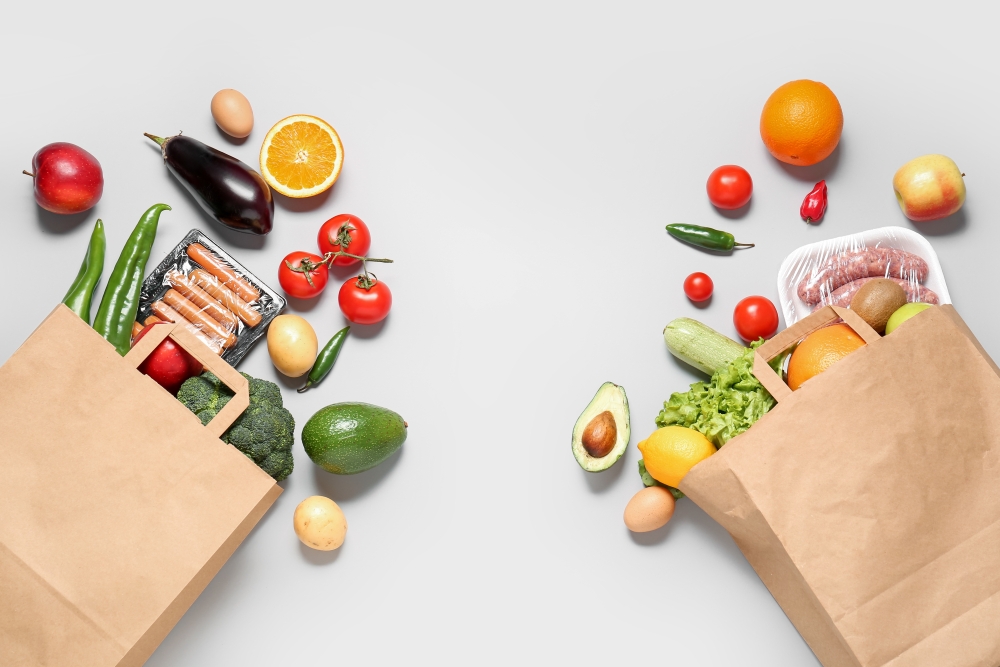 Two brown paper grocery bags with healthy groceries spilling out of them.