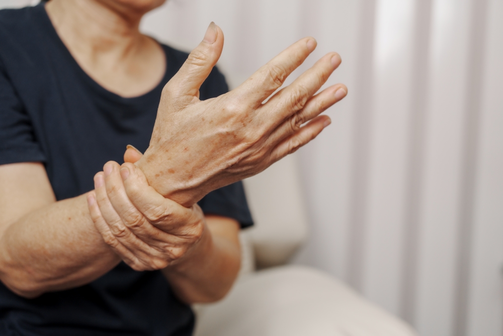 A closeup of a woman clutching her wrist, her palm oustretched.