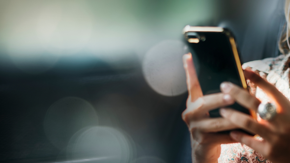 A close-up of a woman's hands holding a smart phone and texting.