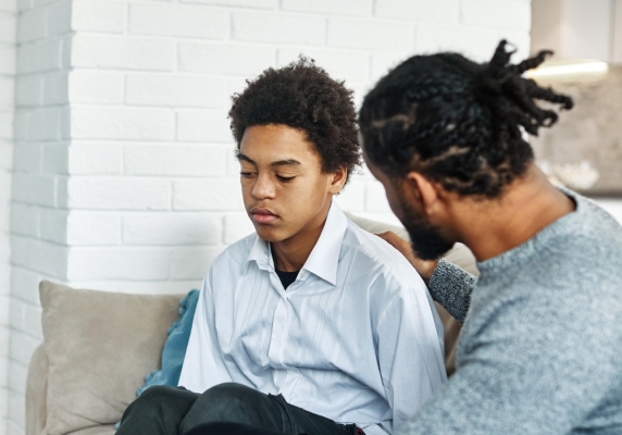 A dad talks to a young teen, who looks like he may be experiencing signs of depression. 