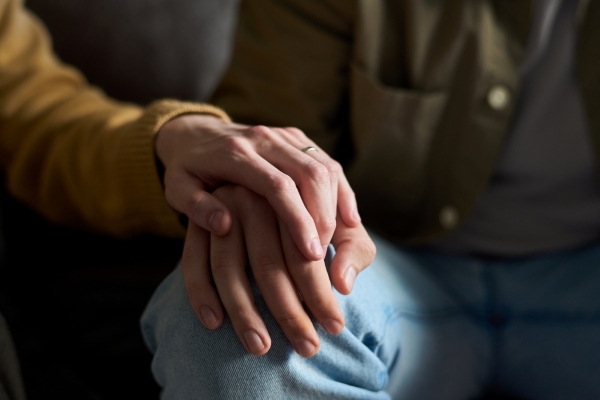 A close up of a woman's hand resting on top of a man's in support. 