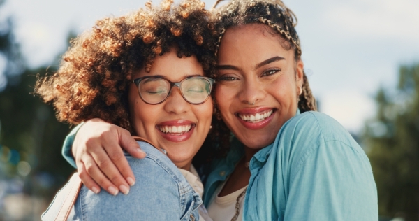 Two women smile and embrace. Social connections are critical for suicide prevention.