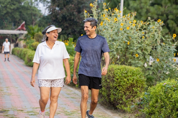 An older couple walking outdoors in a public garden.