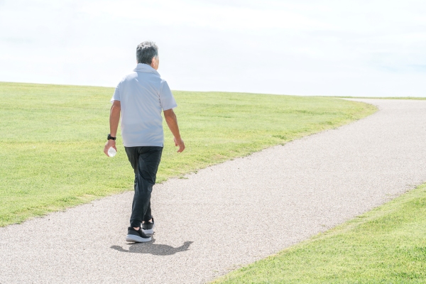 A man carrying a bottle of water goes for a walk outdoors.