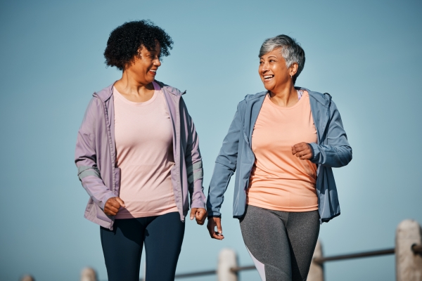 Two older women smile as they take a walk together.